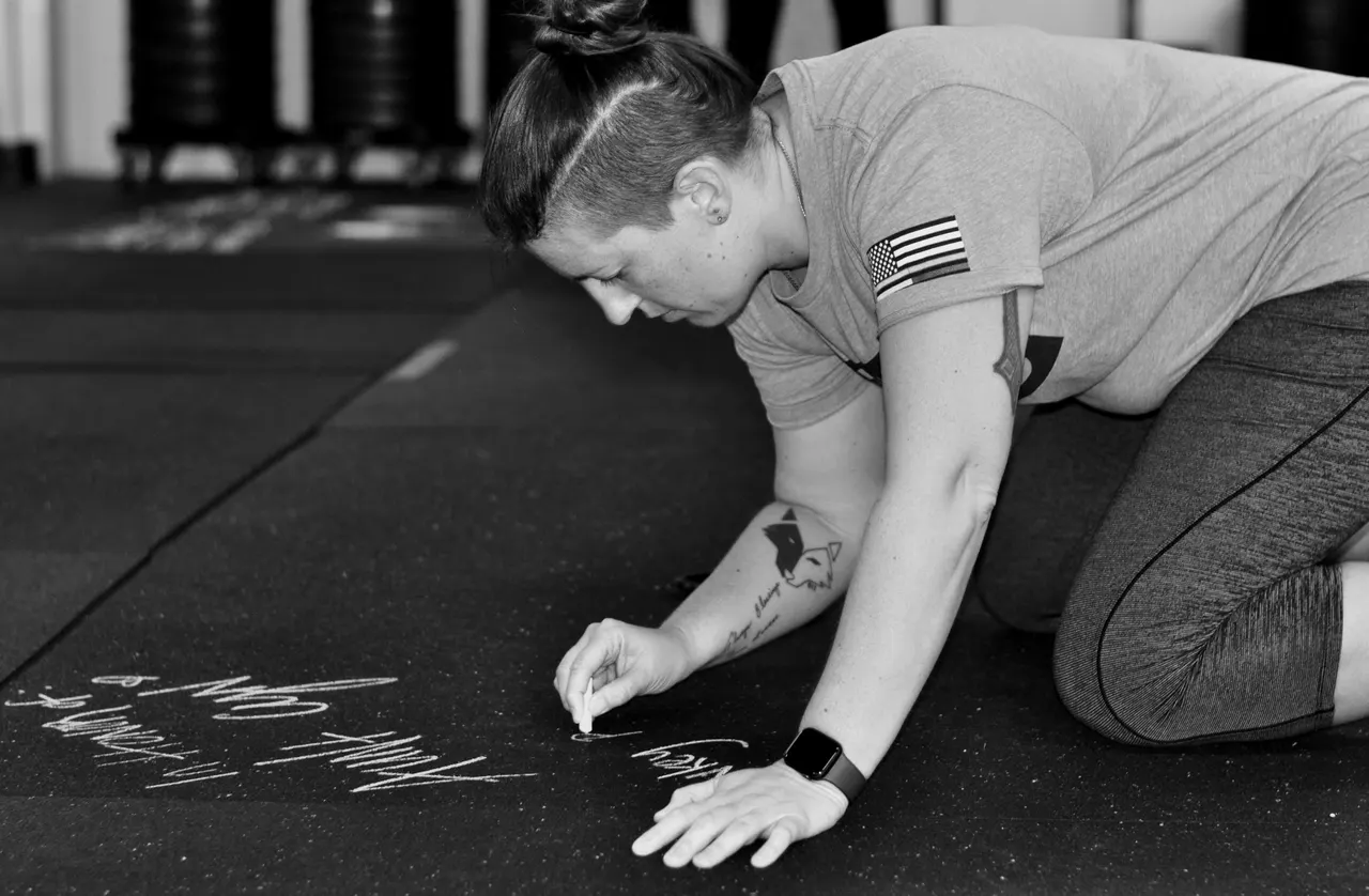 A woman marks the gym floor with chalk before a burpee workout.